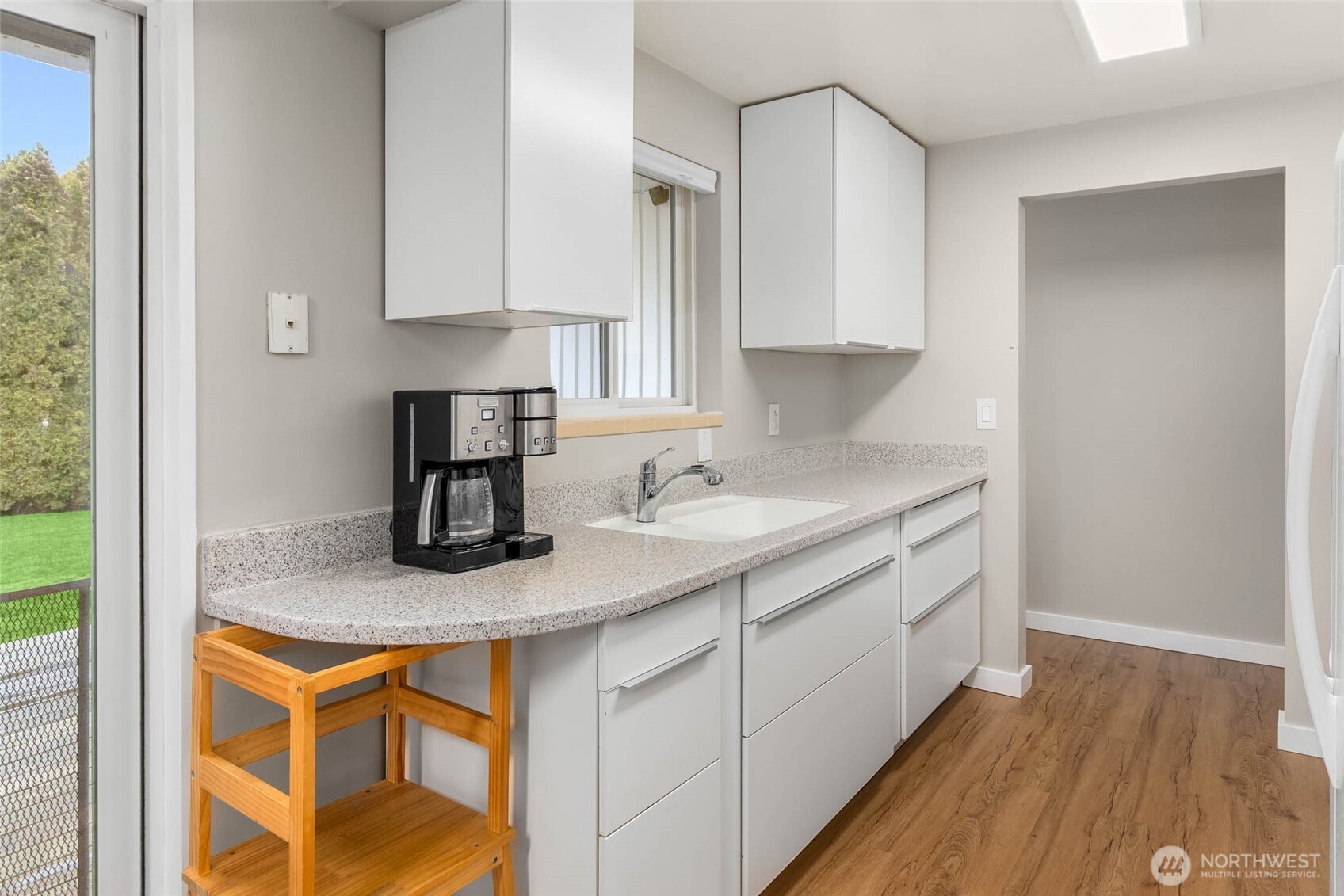 4726 South Victor Street Seattle, WA 98178 - Photo 9 of 30 a kitchen with stainless steel appliances granite countertop a sink a stove and white cabinets with wooden floor