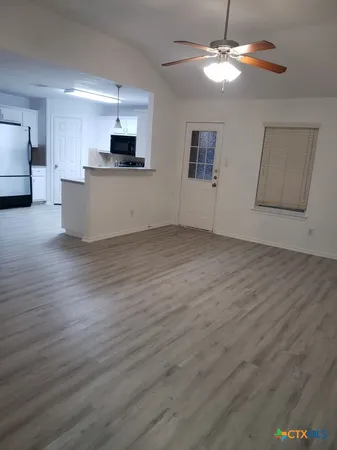 a view of a kitchen with a stove cabinets wooden floor and a ceiling fan