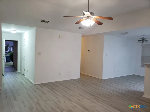an empty room with wooden floor and chandelier fan