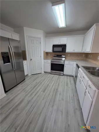 a kitchen with granite countertop a refrigerator and a stove top oven