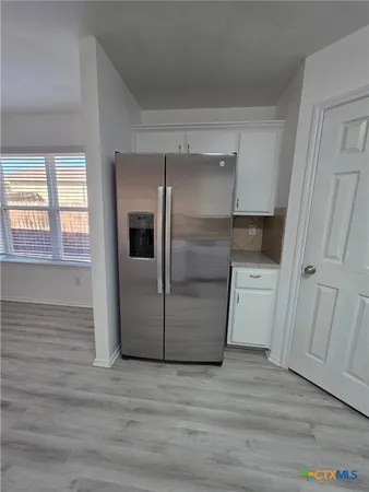 a kitchen with white cabinets and wooden floor
