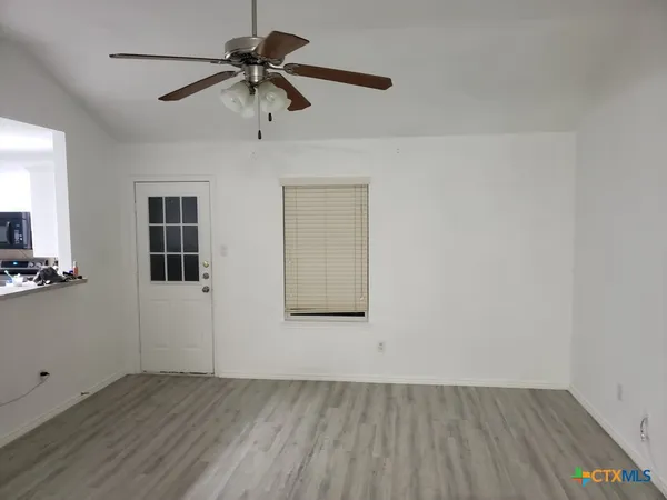 a view of an empty room with a window and wooden floor