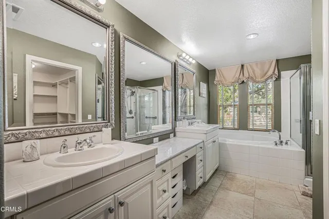 a bathroom with a sink double vanity granite tub shower and a mirror
