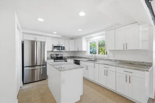 a kitchen with white cabinets stainless steel appliances and a window