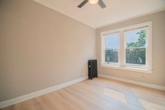 an empty room with a window and a ceiling fan