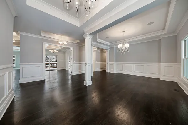 a view of an empty room with wooden floor and a kitchen