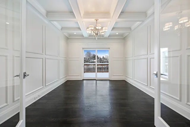 an empty room with wooden floor chandelier and windows