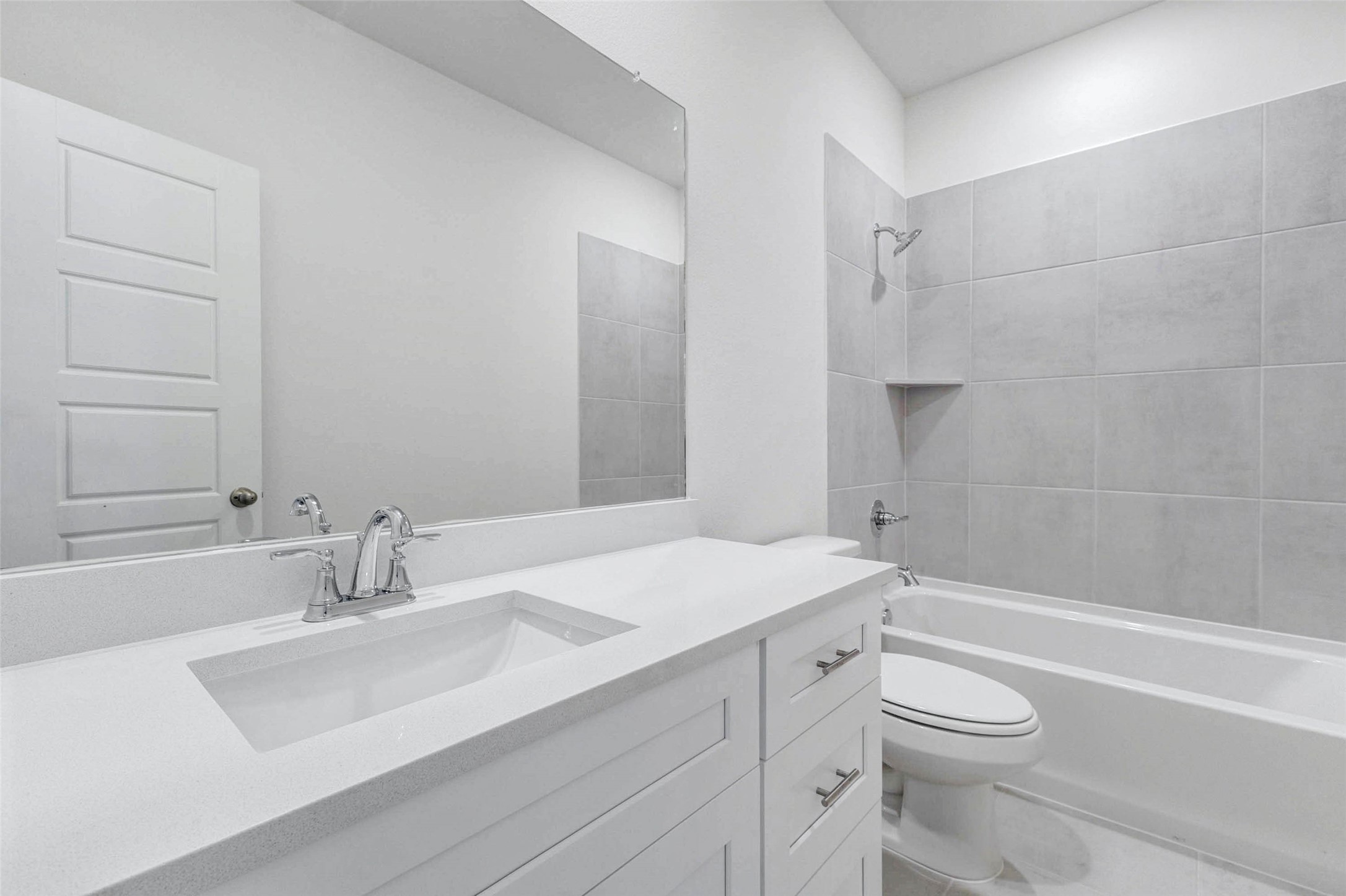 6475 Escondido Drive Rosharon, TX 77583 - Photo 26 of 32 This bathroom offers a bright, clean design with a white vanity, sleek countertop, chrome fixtures, and a large mirror. The tub/shower combination features neutral tile surround and a built-in corner shelf, creating a simple and functional space with fresh finishes that feel easy to maintain.