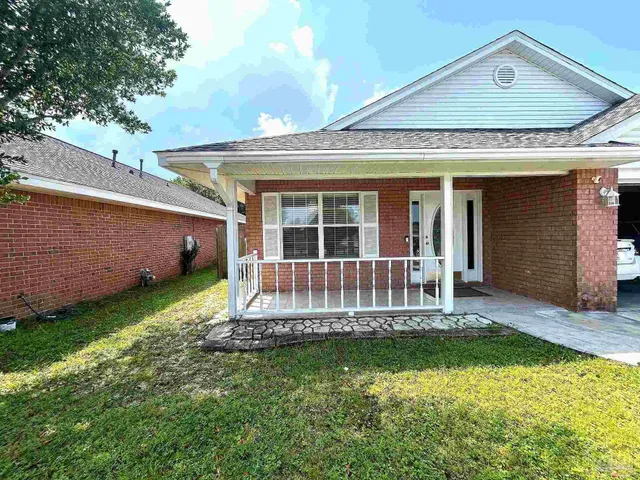 a view of a house with a small yard and a large tree