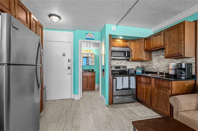 a kitchen with stainless steel appliances granite countertop a refrigerator a stove and a sink