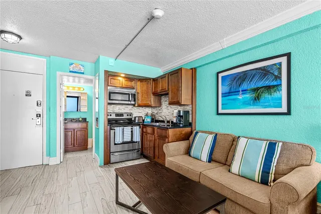 a living room with stainless steel appliances furniture and a kitchen view