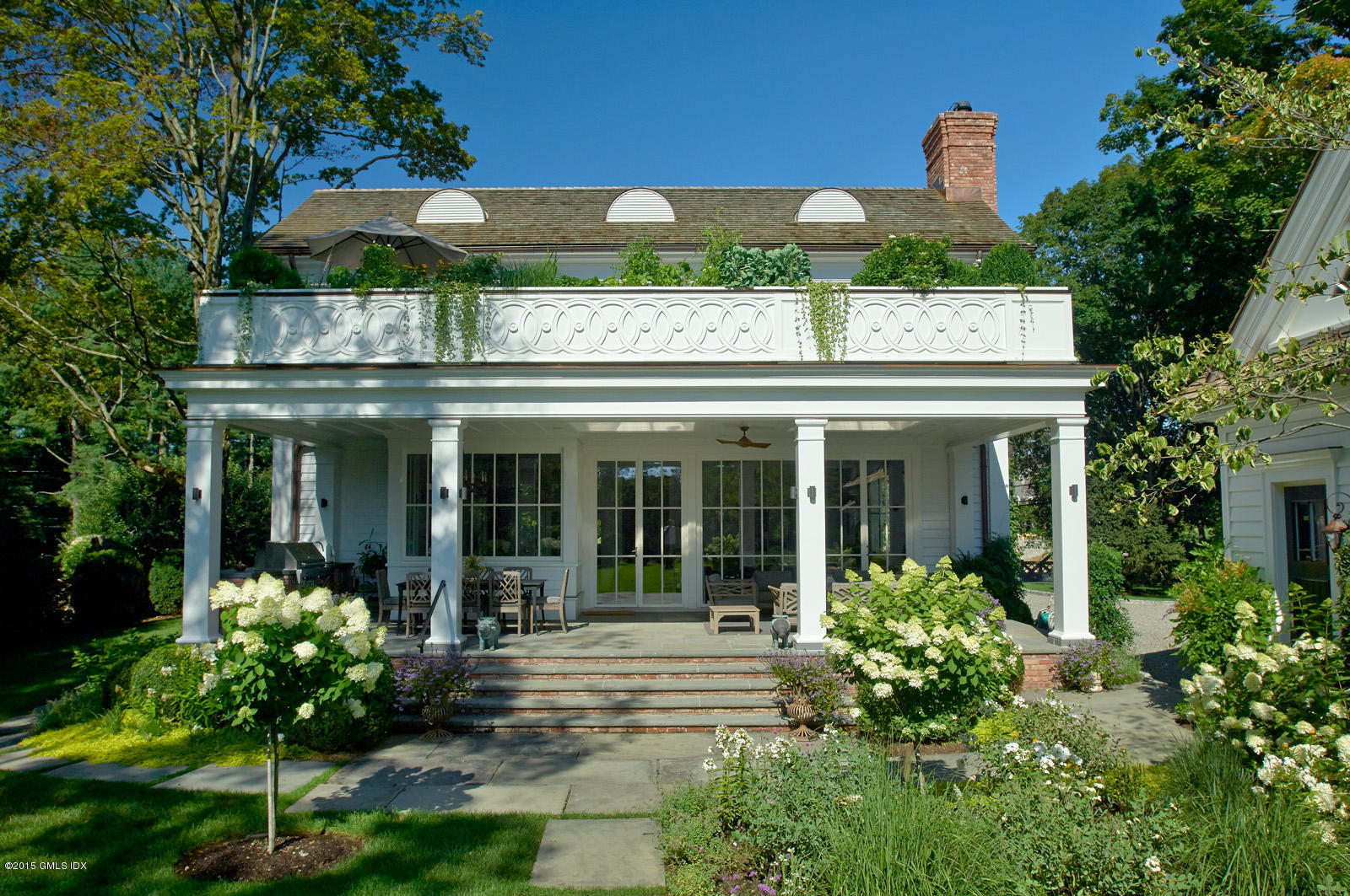 409 Round Hill Road Greenwich, CT 06831 - Photo 3 of 17 a view of a house with potted plants and a table and chairs