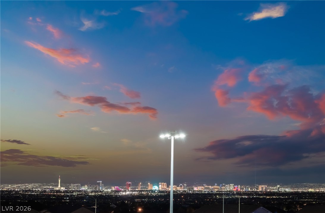 6432 Spring Jog Street Las Vegas, NV 89166 - Photo 58 of 61 Witness the city lights twinkling beneath a vibrant twilight sky from this elevated vantage point.