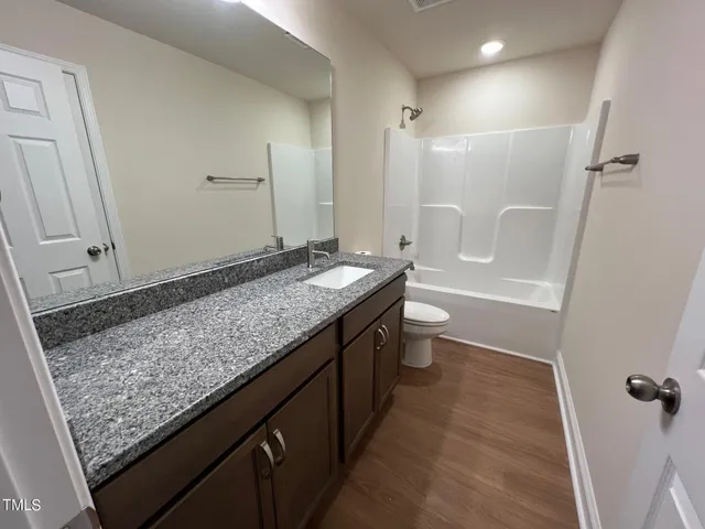 a bathroom with a granite countertop sink a toilet and shower