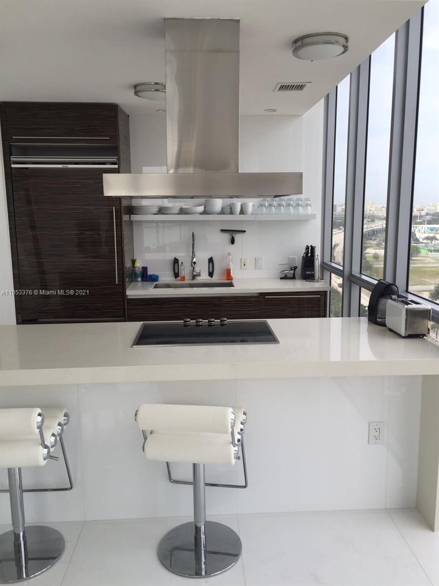 1100 Biscayne Boulevard, Unit 1505 Miami, FL 33132 - Photo 12 of 15 a kitchen with stainless steel appliances a sink and cabinets