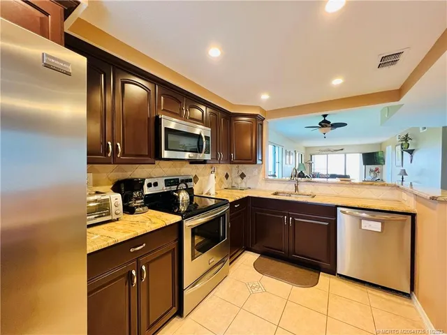 a kitchen with stainless steel appliances granite countertop wooden cabinets a stove top oven a sink and dishwasher