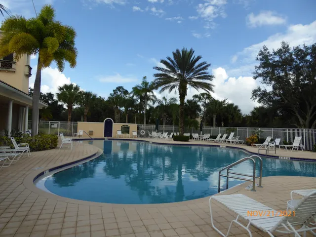 a view of a swimming pool with a lounge chair and palm trees
