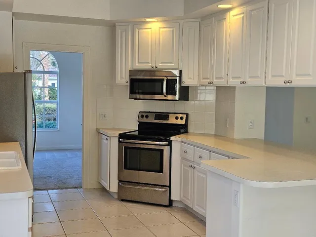 a kitchen with granite countertop white cabinets and stainless steel appliances