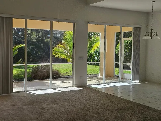 a view of an empty room with floor to ceiling windows and wooden floor