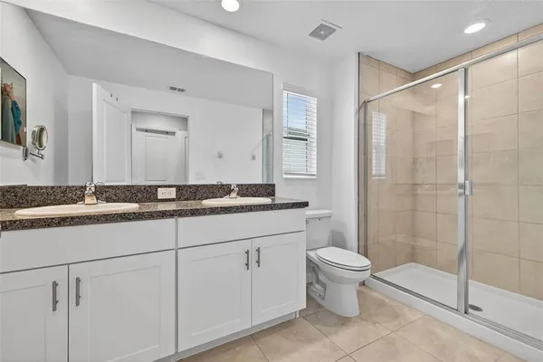 a bathroom with a granite countertop sink a toilet and shower