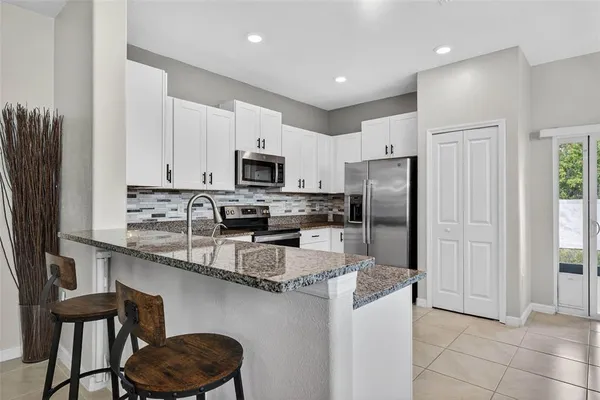 a kitchen with stainless steel appliances granite countertop a sink a stove a refrigerator a center island and chairs
