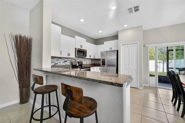 a kitchen with stainless steel appliances granite countertop a refrigerator a stove a sink dishwasher and white cabinets next to a window