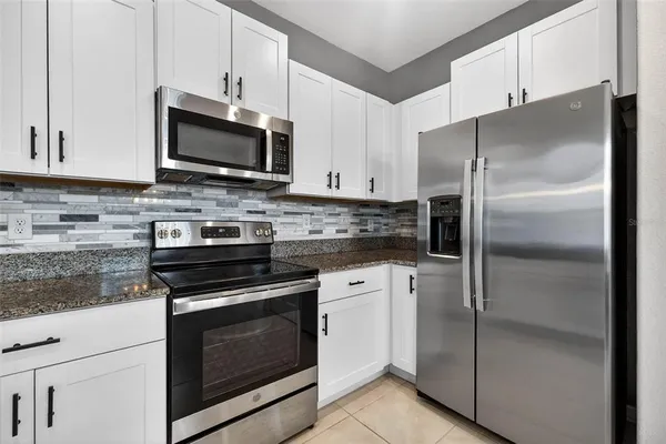 a kitchen with stainless steel appliances white cabinets a sink and a stove