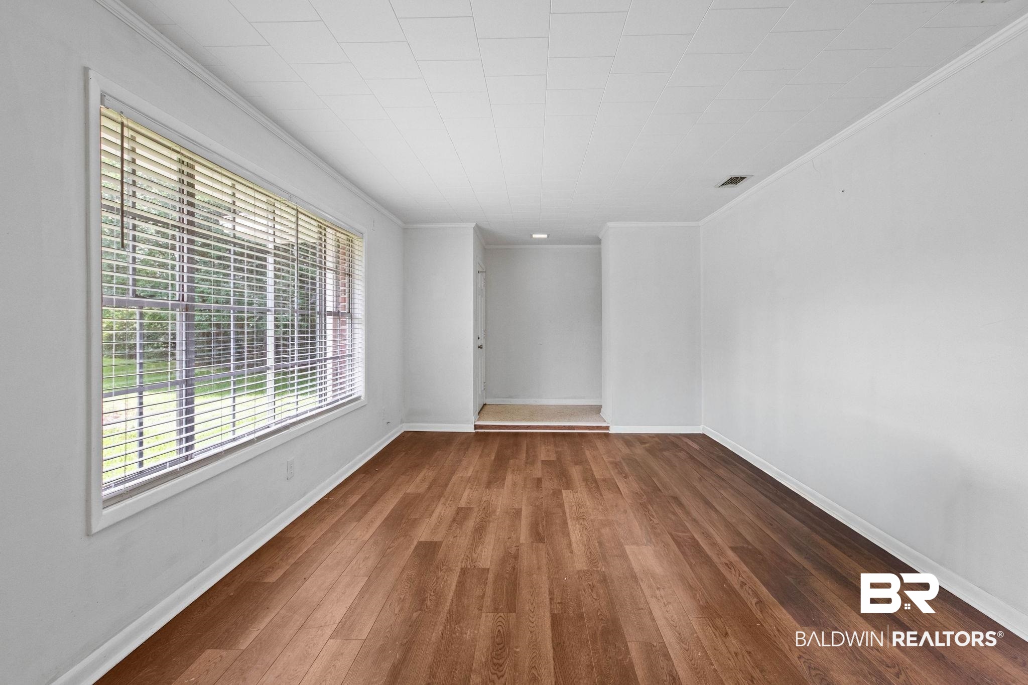 384 Old Bratt Road Atmore, AL 36502 - Photo 31 of 64 Spacious room featuring wood-finish flooring, white baseboards, and a large window with horizontal blinds