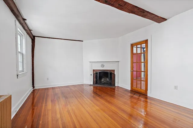 a view of a livingroom with wooden floor and a fireplace