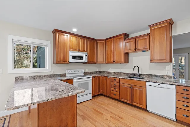 a kitchen with stainless steel appliances granite countertop wooden cabinets sink and window