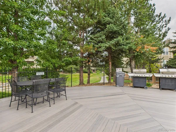 a view of a patio with table and chairs and potted plants with wooden floor and fence