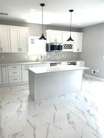 a kitchen with stainless steel appliances kitchen island granite countertop a sink a stove and white cabinets