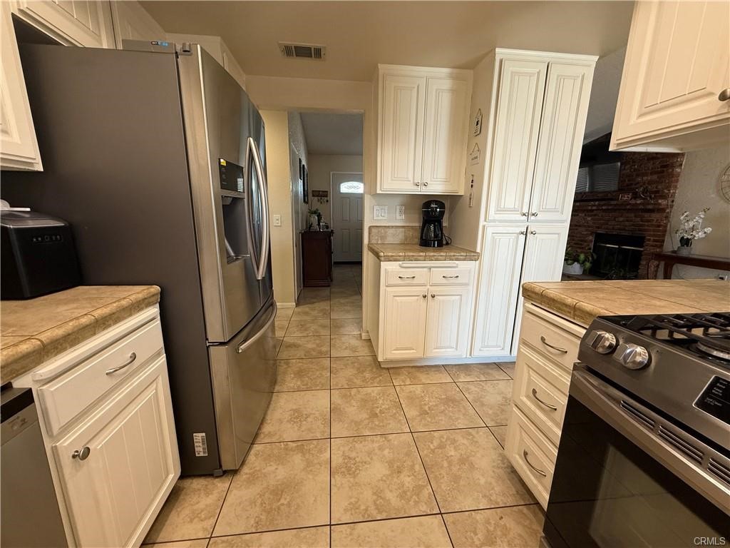 21275 Pocomoke Road Apple Valley, CA 92308 - Photo 11 of 40 a kitchen with white cabinets a refrigerator stove and sink
