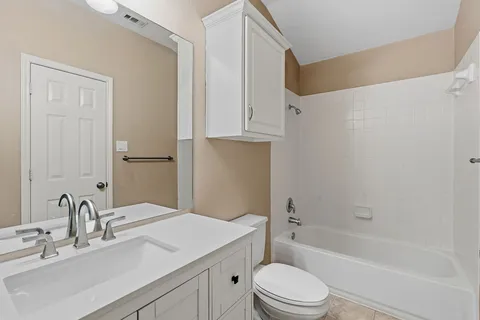 a bathroom with a bathtub shower sink vanity mirror and toilet