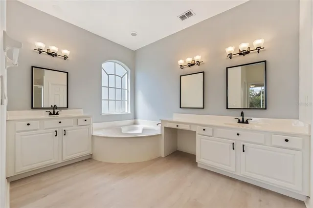 a bathroom with a double vanity sink mirror and bathtub