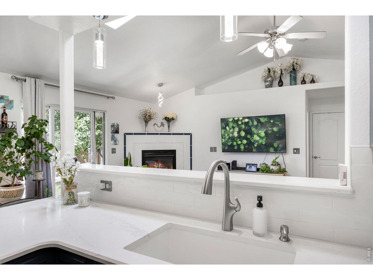148 Beacon Way Windsor, CO 80550 - Photo 17 of 36 Kitchen view overlooking the open living area featuring granite countertops, subway tile backsplash, large single basin undermount sink, updated fixtures, pendant lighting, and vaulted ceilings with an open concept layout.