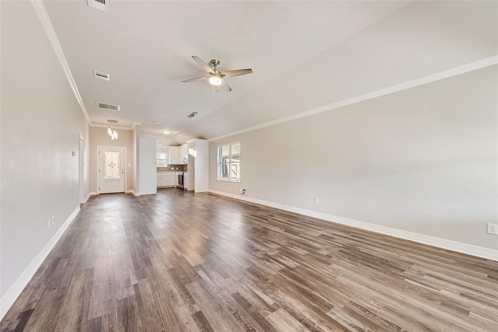 625 Copenhavr Street Pilot Point, TX 76258 - Photo 9 of 20 Unfurnished living room with dark wood finished floors, ornamental molding, and a ceiling fan