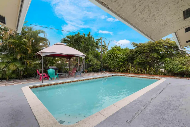 a view of a pool with a table and chairs under an umbrella