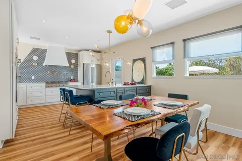 a dining room filled chandelier and kitchen view