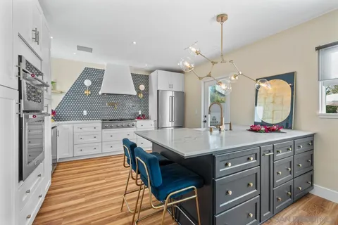 a kitchen with a sink dishwasher a oven with white cabinets and wooden floor