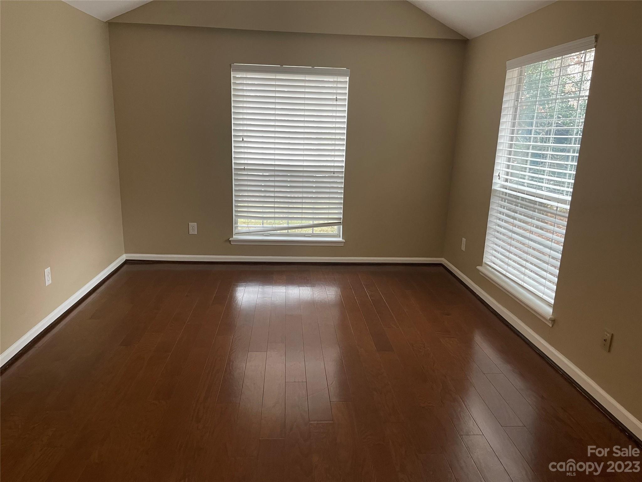 10427 Fairway Ridge Road Charlotte, NC 28277 - Photo 2 of 21 an empty room with wooden floor and windows with curtains