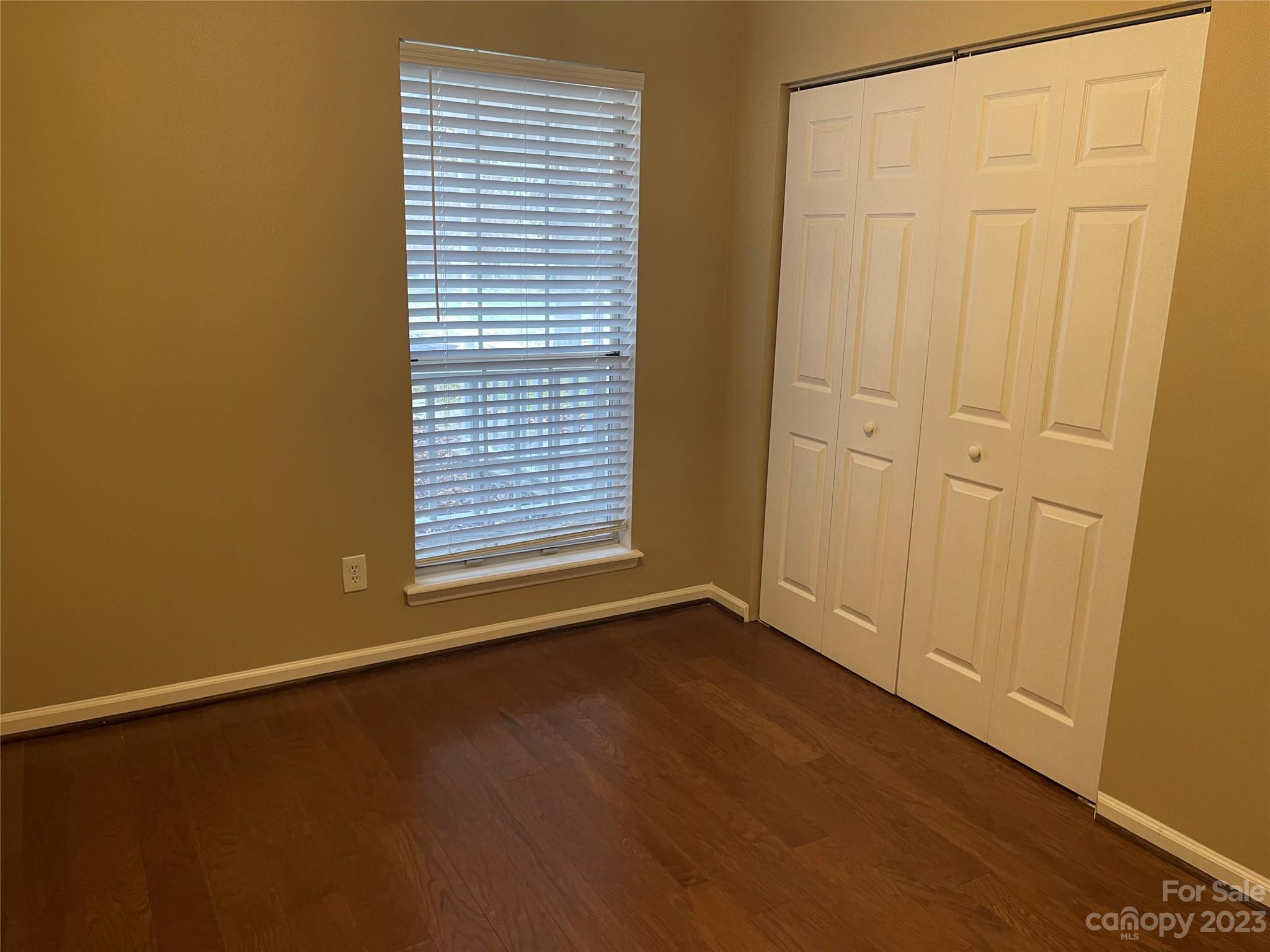 10427 Fairway Ridge Road Charlotte, NC 28277 - Photo 10 of 21 an empty room with wooden floor and windows with curtains