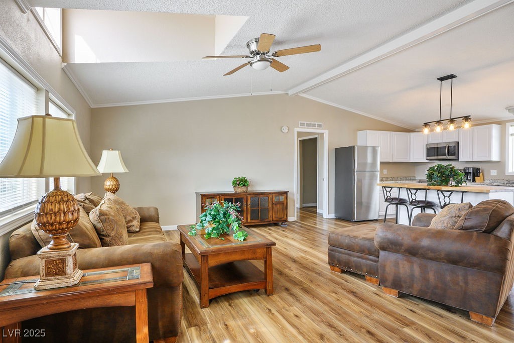 1100 East Gamebird Road Pahrump, NV 89048 - Photo 18 of 37 Living room featuring lofted ceiling with beams, visible vents, light wood-style flooring, ceiling fan, and ornamental molding