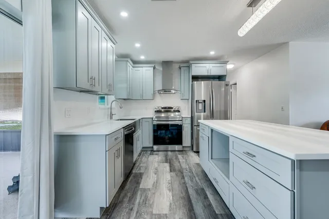 a kitchen with kitchen island granite countertop a sink cabinets and stainless steel appliances