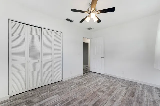 an empty room with wooden floor chandelier fan and closet area