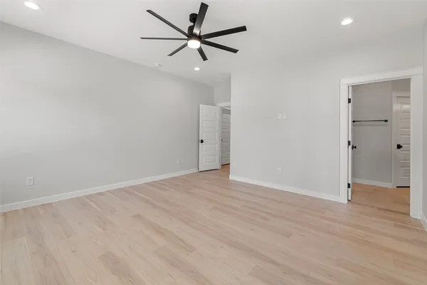 an empty room with wooden floor and a ceiling fan