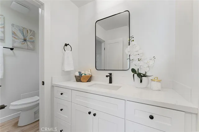 a bathroom with a granite countertop sink vanity mirror and toilet