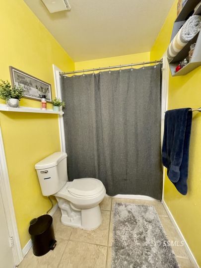 1009 West Iowa Avenue Ridgecrest, CA 93555 - Photo 11 of 26 a bathroom with a toilet and a shower curtain