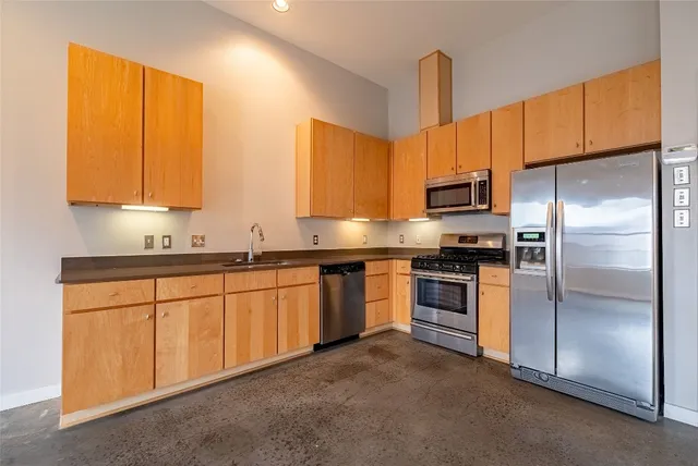 a kitchen with stainless steel appliances granite countertop a refrigerator a sink dishwasher a stove with wooden cabinets