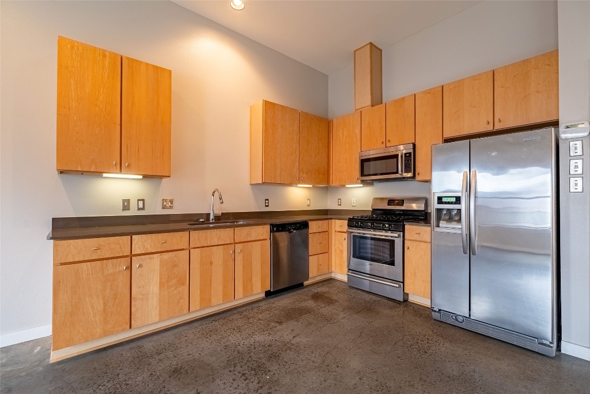 6000 South Congress Avenue, Unit 128 Austin, TX 78745 - Photo 9 of 15 a kitchen with stainless steel appliances granite countertop a refrigerator a sink dishwasher a stove with wooden cabinets